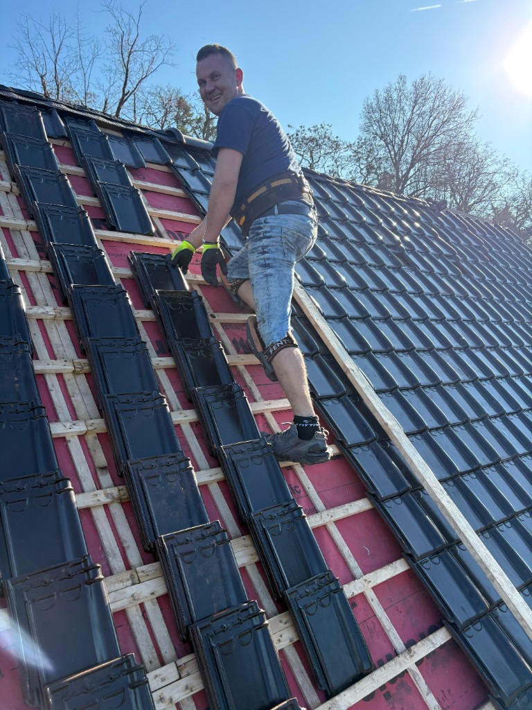 Patrick van Patrick's Dakonderhoud aan het werk op een dak met nieuwe zwarte dakpannen